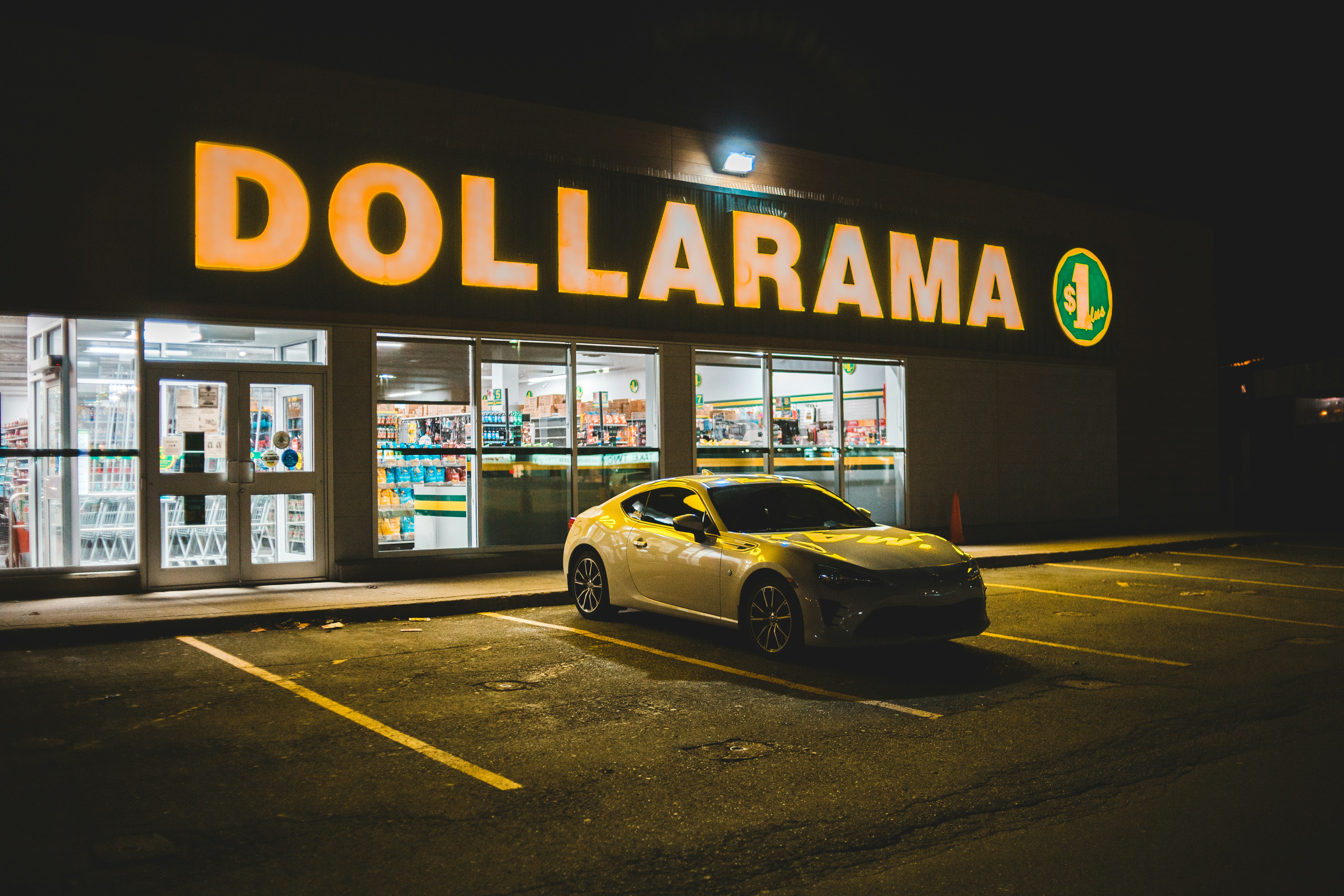 yellow porsche 911 parked beside white and black store